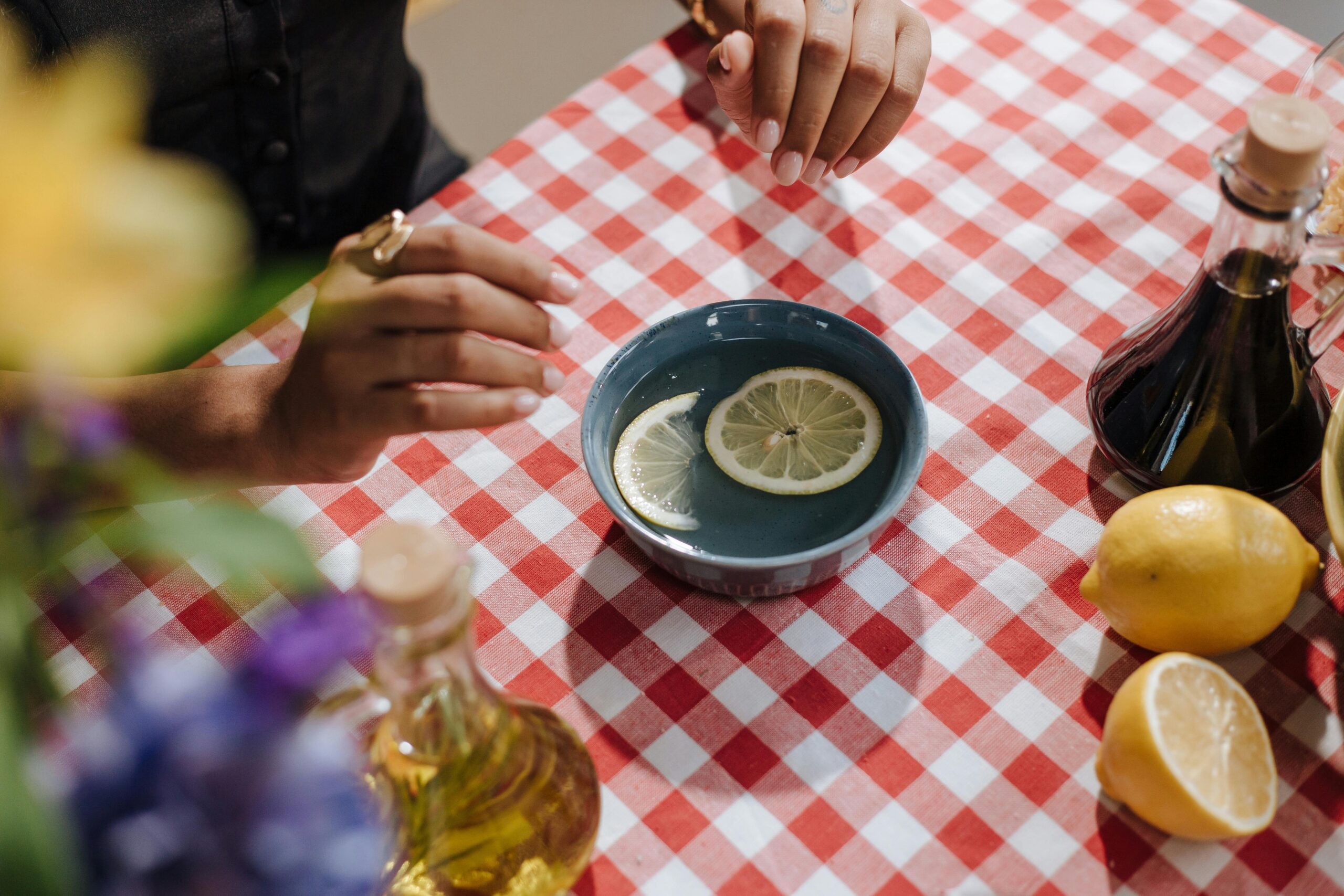 A bottle of white vinegar next to a bowl filled with a mixture of vinegar and water used for sanitizing pet toys.