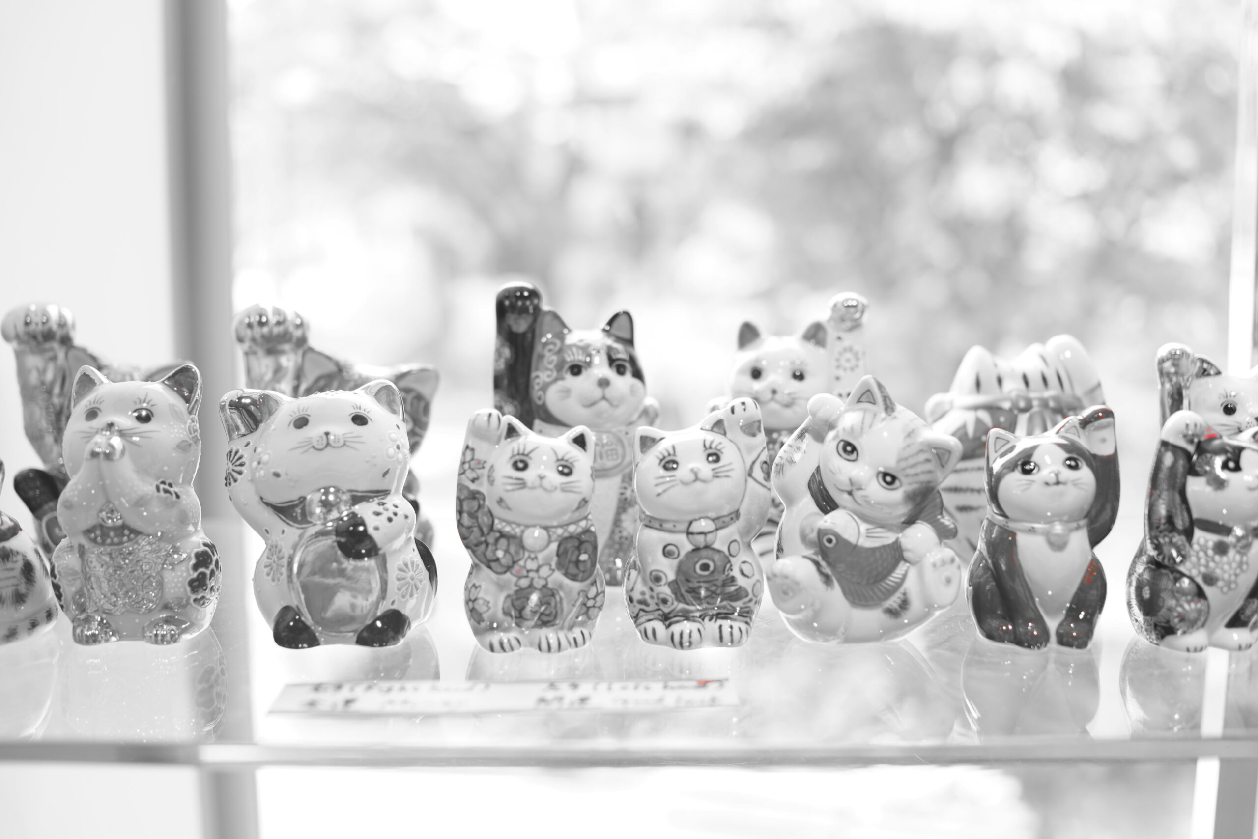 A gray tabby cat batting at a small fish-shaped glass toy near a windowsill