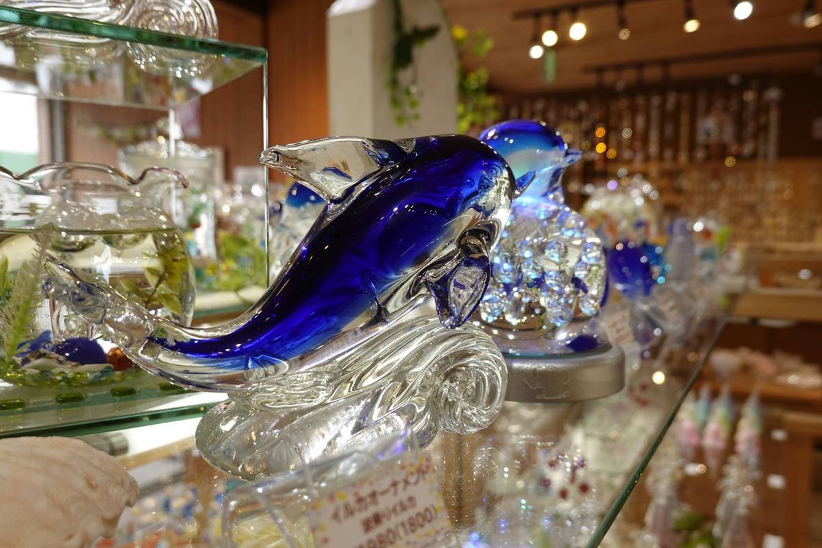 Curious cat pawing at a blue spiral-shaped glass toy