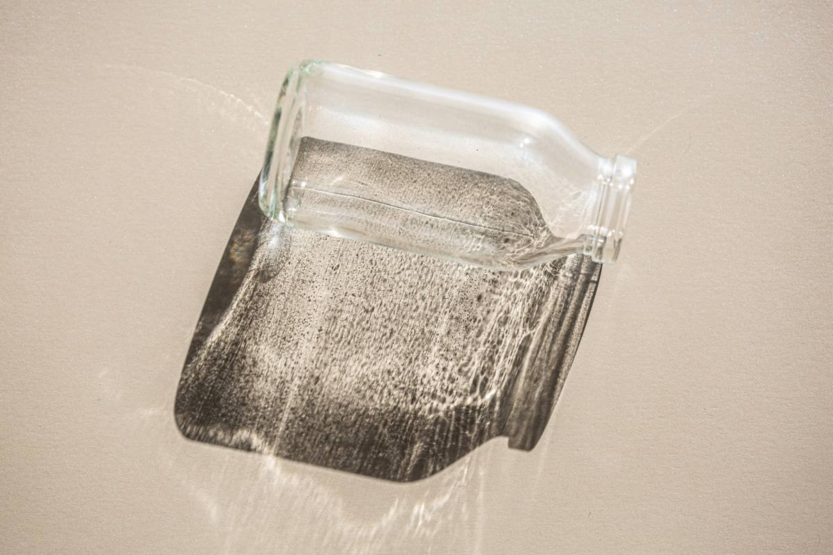 A colorful handmade glass toy shaped like a bone lying on a wooden table